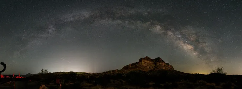 The Milky Way arching over a desert mountain silhouette